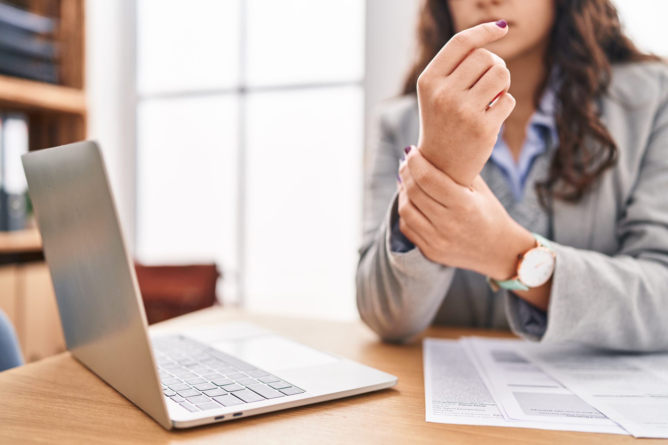 Young hispanic woman business worker suffering for wrist pain at office asesoramiento contable